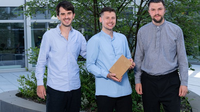 Das Gründungstrio von earthbound steht für ein Gruppenfoto zusammen. Die mittlere Person hält das Produkt, einen Lehmstein, in der Hand